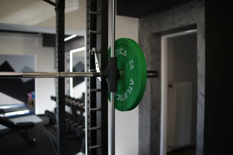 Olympijská tyč se zelenými kotouči v power racku, posilovna FreedomFit Ostrava